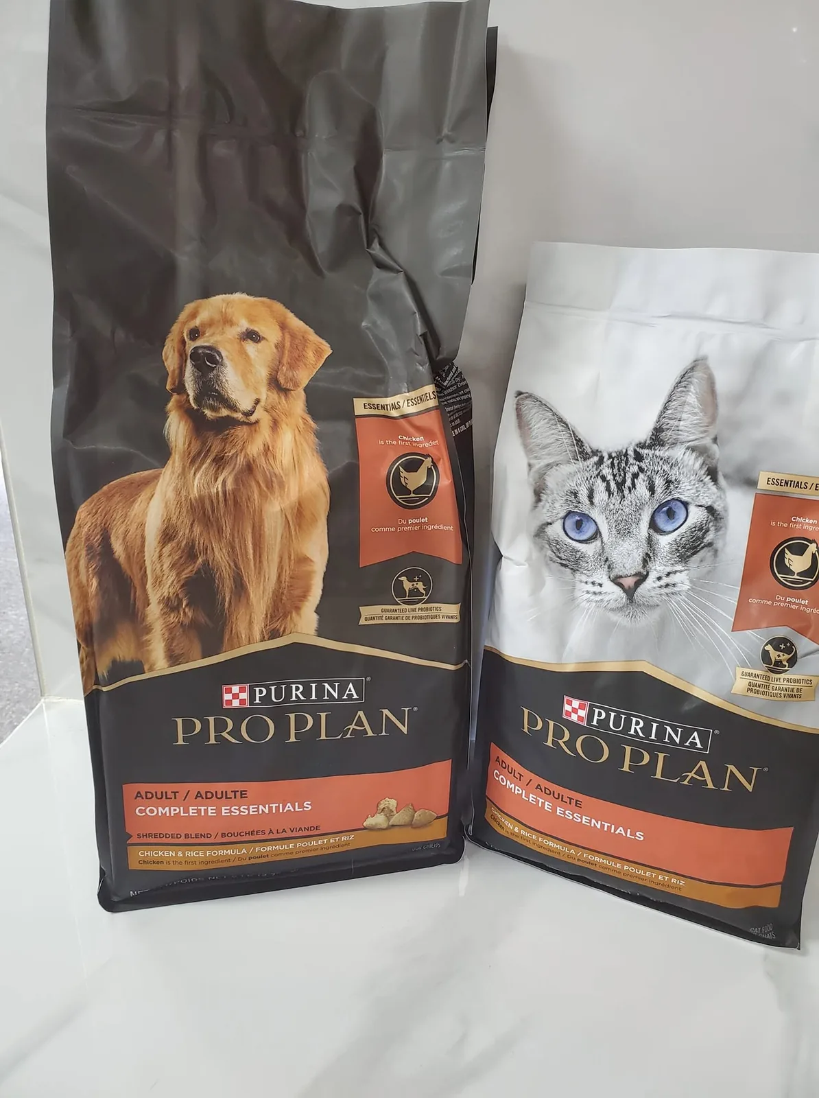 Deux sacs de nourriture sèche, un pour chien et un pour chat, posés côte à côte en boutique.